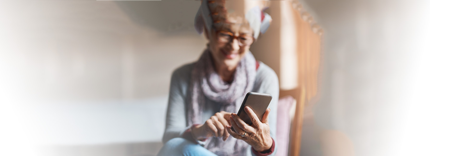Versicherungszeiten für Pension: Seniorin nutzt Smartphone, lächelt glücklich
