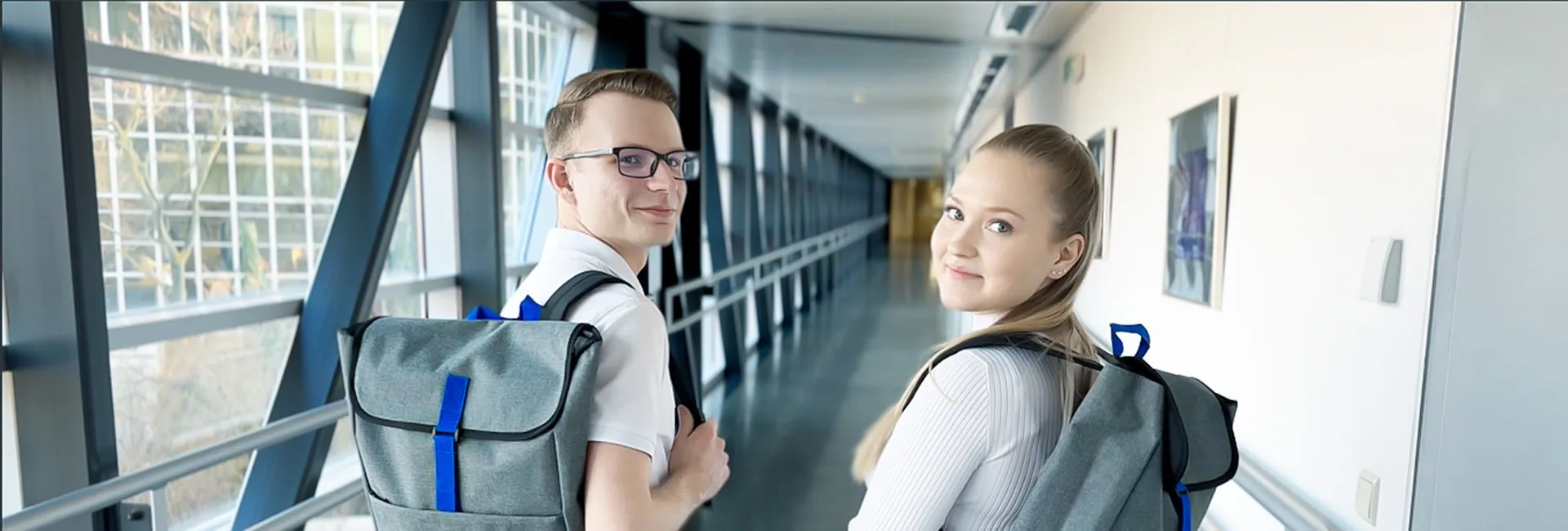 Lehre in der Pensionsversicherung: Junger Mann und junge Frau mit Rucksäcken mit PV-Logo