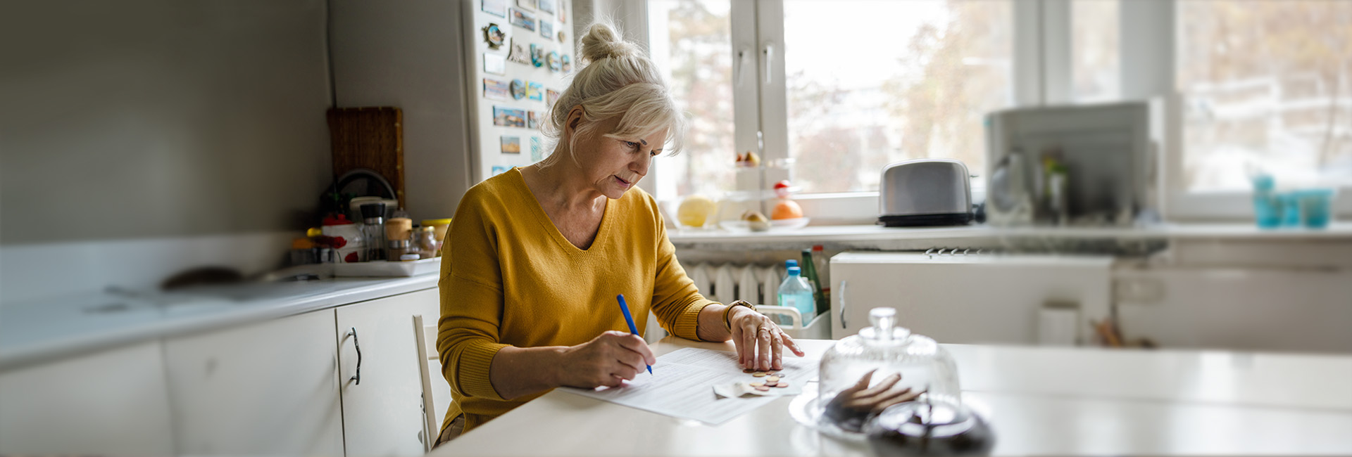 Pensionszahlungsbeleg: Seniorin zu Hause am Küchentisch zählt Geld