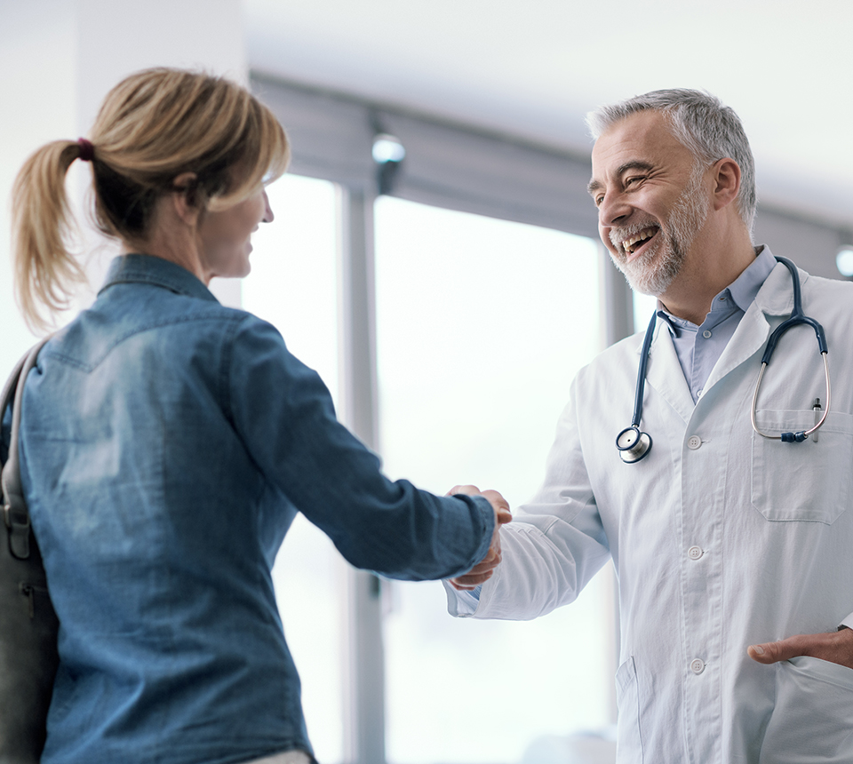 Patientin begrüßt lachenden älteren Arzt