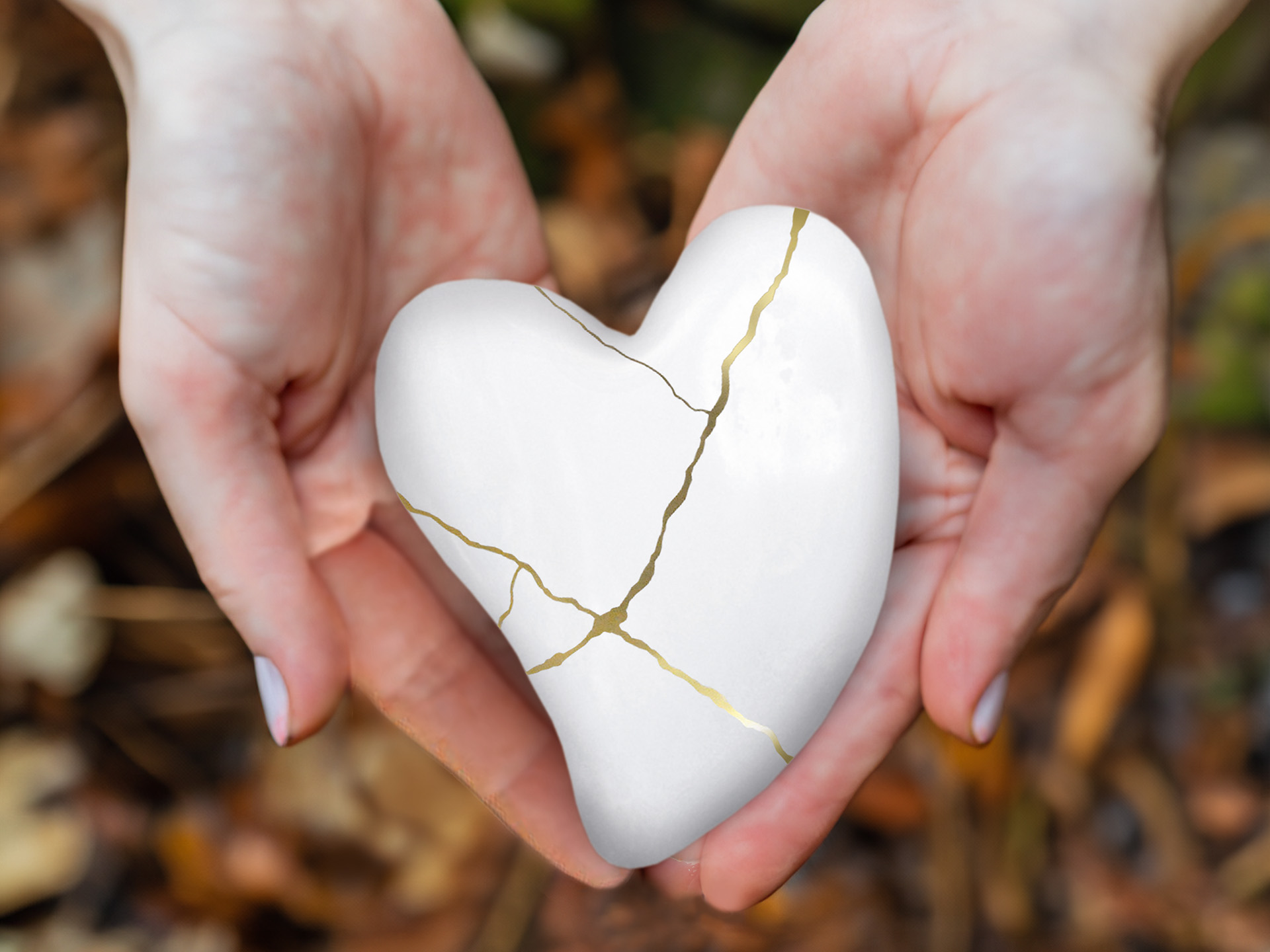 Psychokardiologische Reha: Hände halten weißes Porzellan-Herz mit Riss